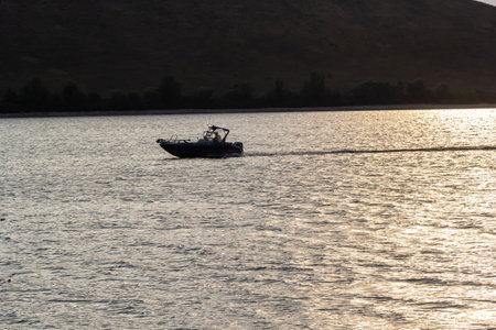 a motorboat sails on the water at high speed. Lake with rocky shores, evening landscape.