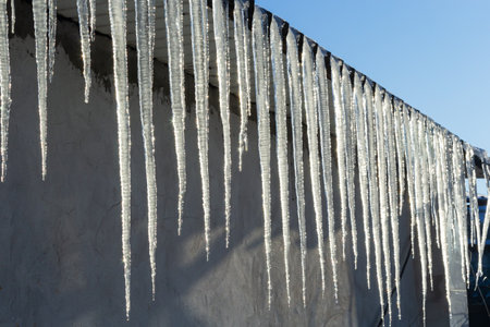 Sharp icicles and melted snow hanging from the eaves of the roof. Beautiful transparent icicles...