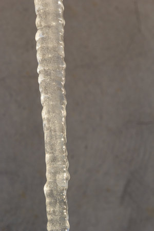Sharp icicles and melted snow hanging from eaves of roof. Beautiful transparent icicles slowly gliding of a roof.の写真素材