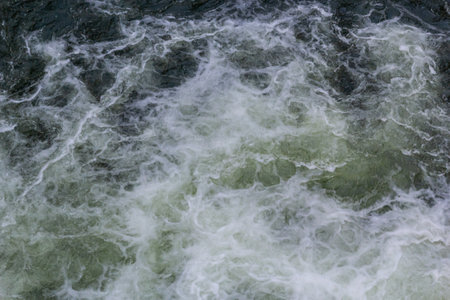 rapids of mountain rivers with fast water and large rocky boulders. Rapid flow of a mountain river in spring, close-up.の写真素材