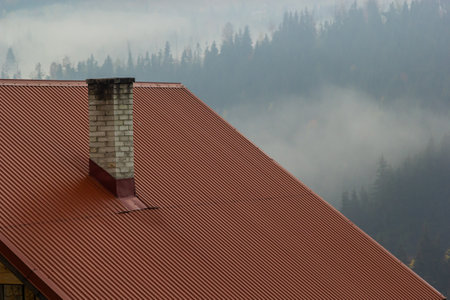 Roof of a new home. Ceramic chimney, metal roof tiles, gutters, roof window. single family house.の写真素材