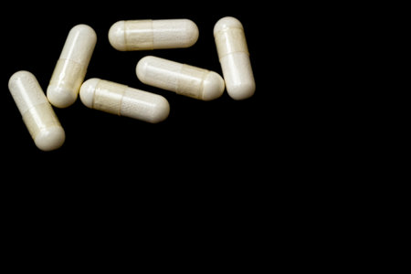 White capsules, pills on a black background with place for text. Medicine, healthcare concept. Range...