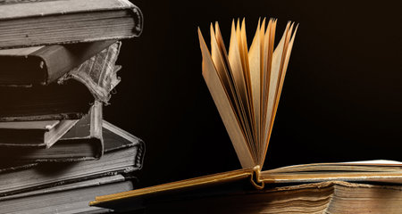 stack of old books with opened one on top on dark background. Old books in the library. bookshelf...