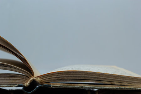 Stack of hardcover old books with an open book on white background.の写真素材