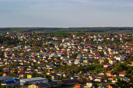 A sprawling residential neighborhood characterized by numerous houses with varied architecture. The landscape features lush greenery and rolling hills in the background, creating a serene atmosphere.の写真素材