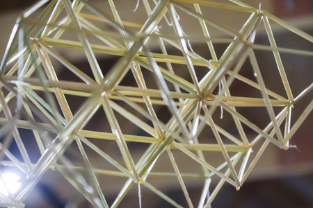Participants construct a geometric model using toothpicks and strings, engaging in a creative and educational activity within a bright workspace setting.の写真素材