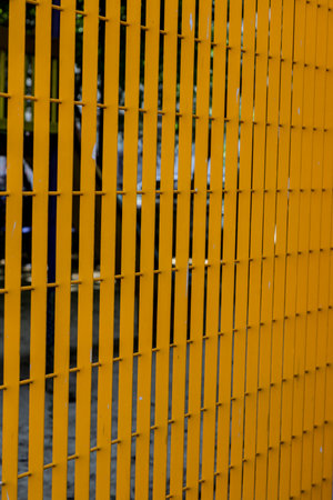 A vibrant yellow fence creates a striking visual contrast against a darker backdrop, showcasing a...