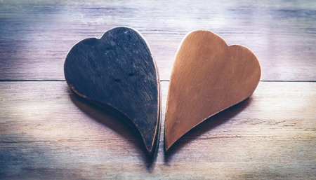 Two distinct halves of a heart represent the search for companionship and love, resting on a rustic wooden background.の素材