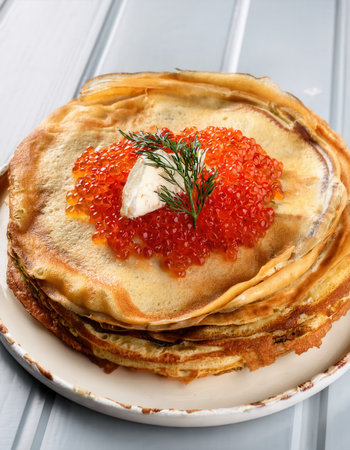Enjoy a generous stack of savory crepes adorned with caviar and salted fish, prepared to your liking at Firefly.の素材
