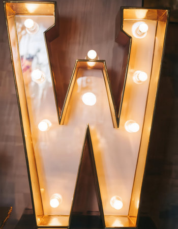 A stylish lit-up mirror in the shape of the letter W adds charm to the cozy indoor atmosphere during the evening.の素材