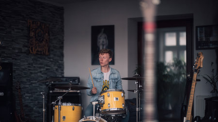In a garage filled with music gear a drummer in a wheelchair enjoys playing drums fully immersed in the rhythm of the moment.の素材