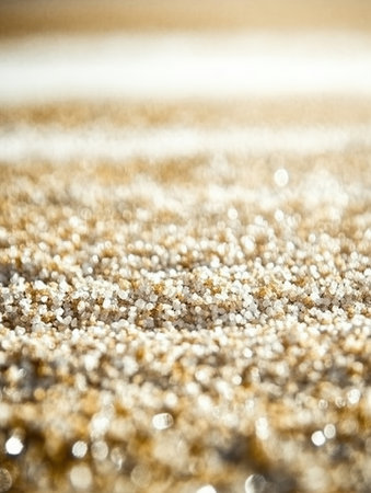 view of fine white sand grains shimmering under the soft glow of sunset next to gentle waves lapping at the shore creating a tranquil scene.の素材