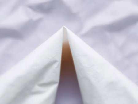 A folded piece of white paper is displayed showing a sharp triangular point. The smooth surface contrasts with the backdrop creating a calming visual effect.の素材