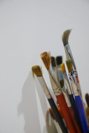 Various paintbrushes are neatly placed in a holder, showing different sizes and shapes, with their...