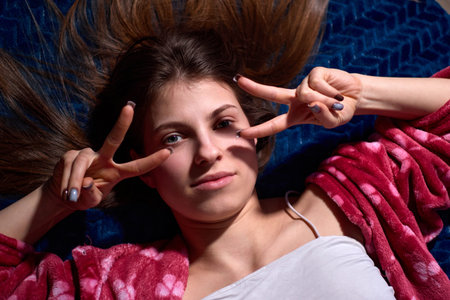 Attractive young woman lying on a blue textured blanket, her beautiful hair spread around her,...