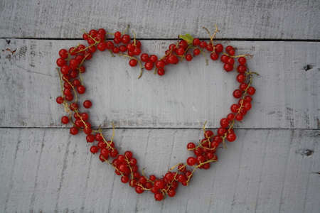 Fresh washed currants berries in a heart shaped bowl on gray with copy space.