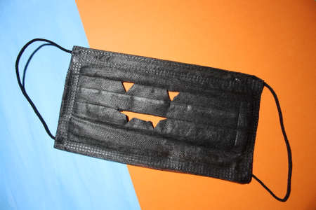 Black medical facial mask isolated on orange background closeup. Halloweenの写真素材
