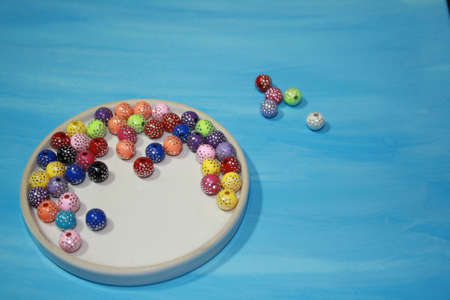 Colored decorative beads on a glass transparent saucer. Top viewの写真素材