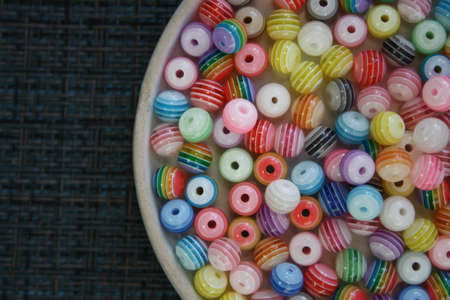 Colored decorative beads on a glass saucer. Top view