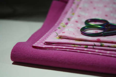 Sewing accessories and fabric close-up. Pink cloth