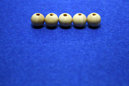 Wooden beads spread on blue background. Space for text.