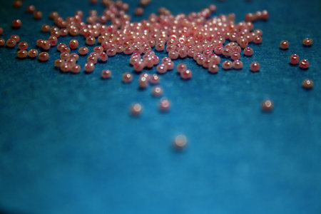 Pink beads on the blue felt background. Space for textの写真素材