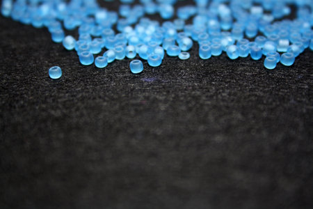Blue beads on a black felt background. Space for text.の写真素材