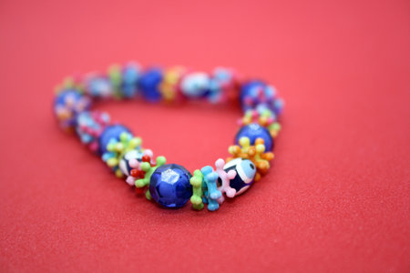 A bracelet made of beads on a red background. Space for text.