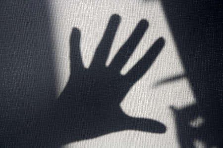 A figure in the shadow of the sun on a gray wall. Background for the text.