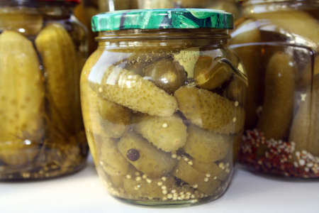 Jar of pickled cucumbers on a black background. Space for text.