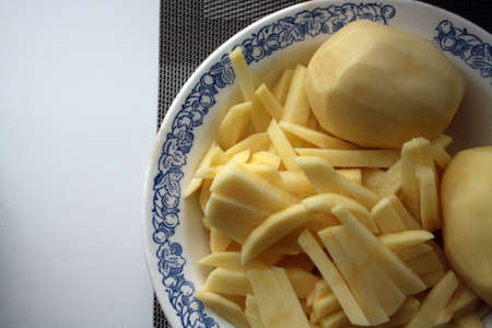 Peeled potatoes ready to cook. Culinary background. Space for text.