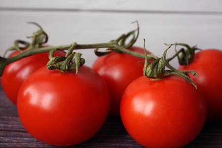 Red tomatoes on a branch on a wooden background. Space for text.の写真素材