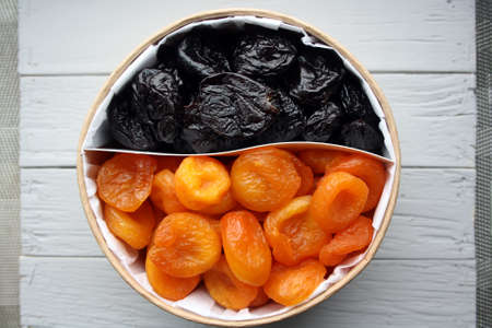 Dried fruits. Dried apricots and prunes on a wooden background. Space for text.の写真素材