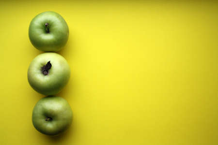 Juicy yellow apples on a yellow background. Space for text.の写真素材
