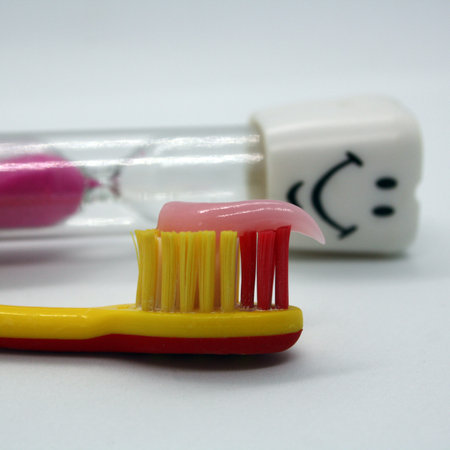 Children's toothbrush with paste and an hourglass. Space for text.