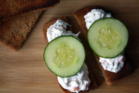 Cottage cheese dip with cucumber slices on black bread toast. Breakfast. Space for text.の写真素材