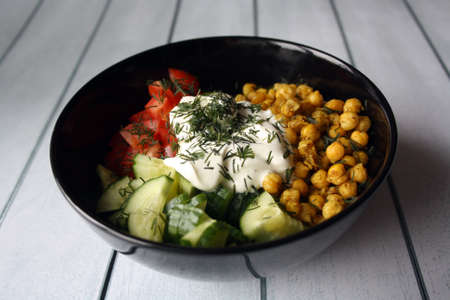 Chickpeas, tomatoes, cucumbers. Ingredients for the salad in a black bowl. Culinary background.の写真素材