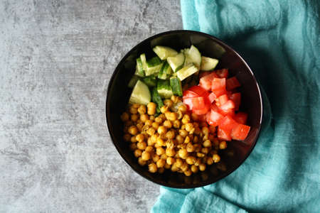 Chickpeas, tomatoes, cucumbers. Ingredients for the salad in a black bowl. Culinary background.の写真素材