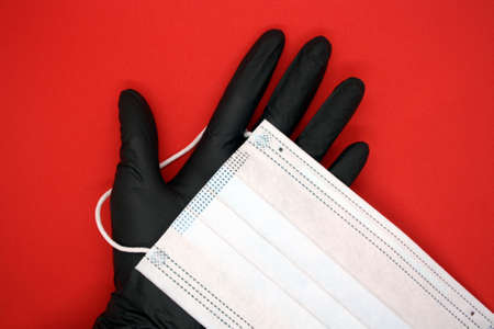 Medical mask and black gloves on red background.の写真素材