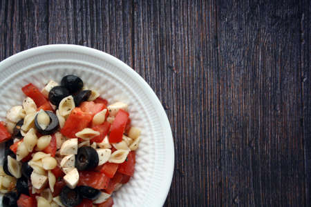 Italian salad with pasta, tomatoes and mozzarella. Culinary background. Space for text.の写真素材