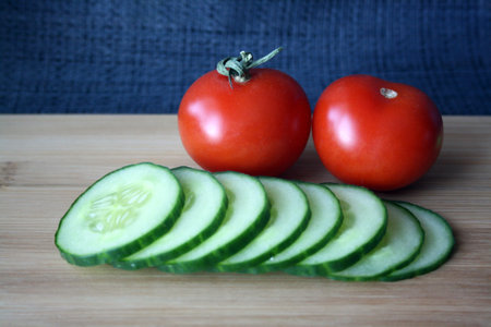 Tomatoes and cucumbers on a wooden board. Space for text.の写真素材