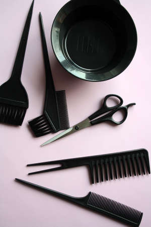 A set of tools for a hairdresser. Black scissors and a comb on a pink background.の写真素材