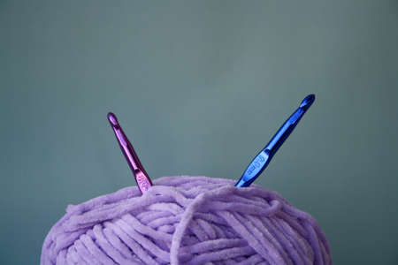 Women's hobby. Crochet and knitting. Purple yarn and crochet hooks on the table. Working space.