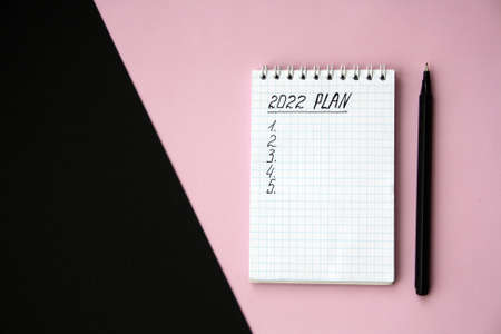 2022 notebook mockup on pink background. New Year. Plans, goals for 2022, space for text in a...
