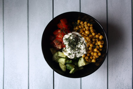 Chickpeas, tomatoes, cucumbers. Ingredients for the salad in a black bowl. Culinary background.の写真素材