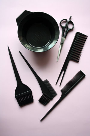 A set of tools for a hairdresser. Black scissors and a comb on a pink background.の写真素材
