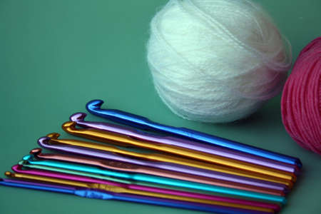 Women's hobby. Crochet and knitting. White, pink yarn and crochet hooks on the table. Working space.の写真素材