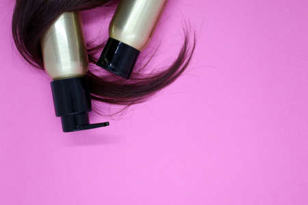 Lock of female light brown hair, hair care products on pink background. Top viewの写真素材