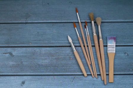 Set of artistic paintbrushes on blue wooden background. Top view