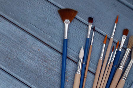 Set of artistic paintbrushes on blue wooden background. Top viewの写真素材
